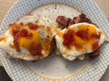 Load image into Gallery viewer, Two fried eggs with Original Chilli Relish (chilli jam) on top of bacon rolls on a plate with a blue and white pattern.