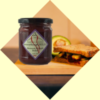 Load image into Gallery viewer, Oooft!  A 200g jar of everythingCHILLI Beetroot &amp; Apple Relish – deep red chunky relish in a glass jar with branded label, in front of a cheese and avocado sarnie
