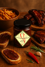 Load image into Gallery viewer, Jar of &#39;everything CHILLI&#39; marinade on a wooden surface with bread, chilli, herbs and garlic.
