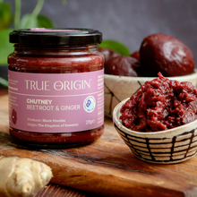 Load image into Gallery viewer, Jar of True Origin chutney with beetroot and ginger on a wooden board.

