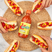 Load image into Gallery viewer, Hot dogs with Valentine&#39;s hot sauce on a woven mat, surrounded by hands holding the hot dogs.
